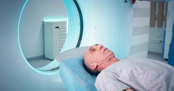 Oudere man liggend op CT machine tafel — Stockvideo