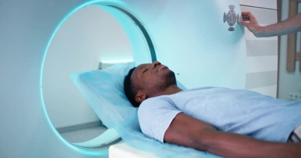 アフリカ系アメリカ人患者がクリニックでCT装置に入る — ストック動画