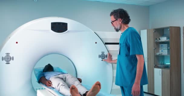 Rijpere arts raadplegen zwarte patiënt voor CT scannen — Stockvideo