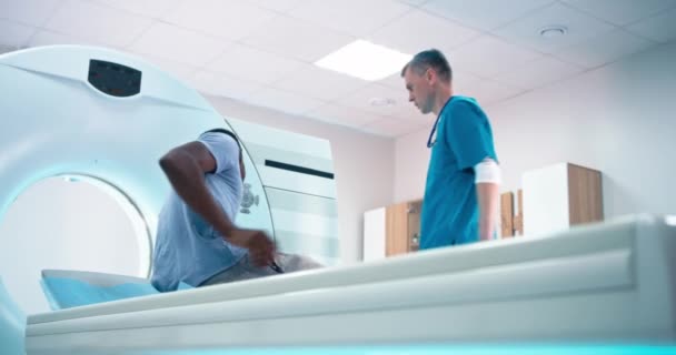 Rijpere arts instrueren zwarte man voor CT scanprocedure — Stockvideo