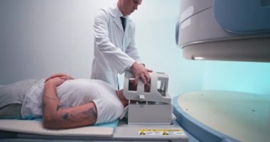 Sakallı adam orta yaşlı doktorla beyin MR 'ına başlıyor.