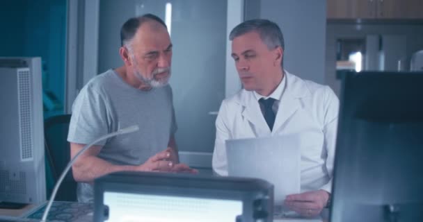 Mature doctor discussing medical test results with senior patient — Stock Video