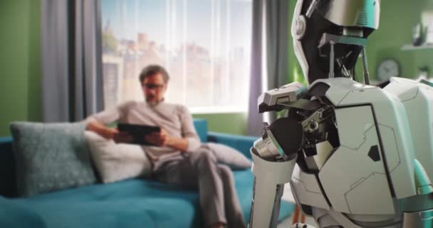 Hombre maduro apagando robot androide en casa — Vídeos de Stock