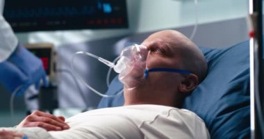 Hasat doktoru solunum maskeli kanser hastasına nabız oksimetresi uyguluyor.