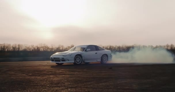 Beyaz araba bulutlu gün batımına doğru sürükleniyor. — Stok video