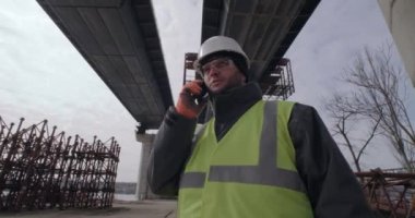 Erkek müteahhit akıllı telefondan konuşuyor.