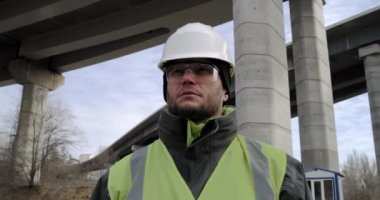 Erkek müteahhit köprünün altına bakıyor.