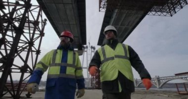 Köprü altında yürüyen erkek inşaatçılar