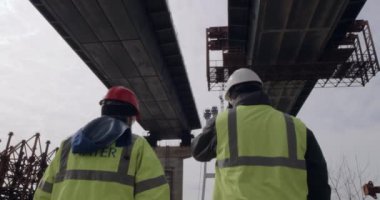 Köprü inşaatını inceleyen tanınmayan adamlar