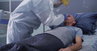 Koğuştaki yaşlı bir hastadan COVID testi alan bir tıp doktoru.