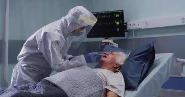 Γιατρός που κάνει εξέταση κορωνοϊού από γκρινιάρη ηλικιωμένο ασθενή — Αρχείο Βίντεο
