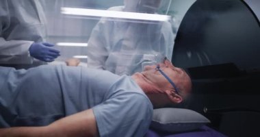 Çok derin nefes alan yaşlı bir hastanın yanında konuşan tıp doktorları.