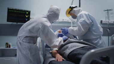 Doktorlar yaşlı hastaya oksijen pompalıyor.