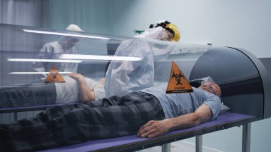 Sağlık görevlileri hiberbarik odalarda yaşlı adamları kontrol ediyorlar.