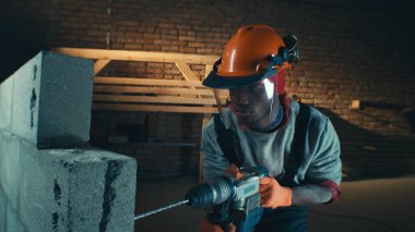 Kara müteahhit karanlık odada tuğla duvar kazıyor.