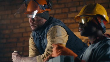 Çeşitli inşaatçılar öğle arasında konuşuyor.