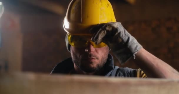Mannelijke timmerman die tijdens het werk zijn helm aanpast — Stockvideo