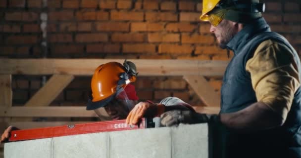 Constructores multirraciales midiendo muro de ladrillo — Vídeo de stock