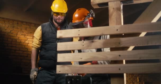 Çeşitli erkek marangozlar kereste tahtalarını birlikte kesiyorlar. — Stok video