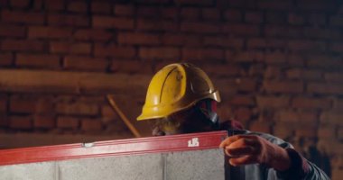 Siyah müteahhit tuğla duvarı ölçüyor.