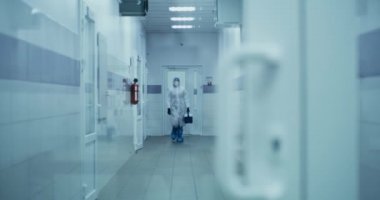 Doktor laboratuvar koridorunda kutu taşıyor.