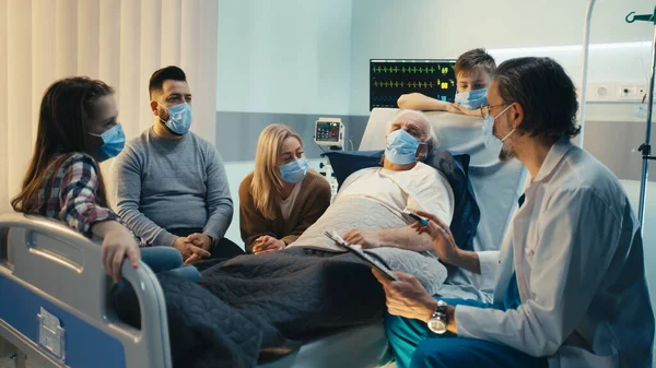 Mature doctor speaking with senior patient and family — Stock Photo, Image