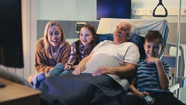 Paciente anciano y visitantes viendo televisión juntos — Foto de Stock