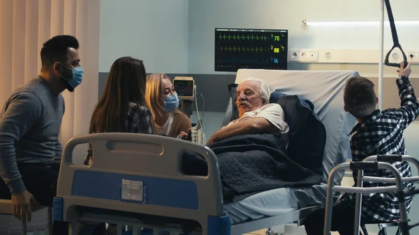 Старший пациент разговаривает с семьей в клинике — стоковое фото