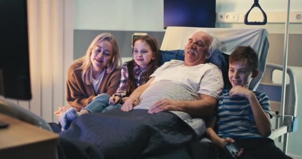 Idős beteg és a látogatók együtt nézik a tévét — Stock videók