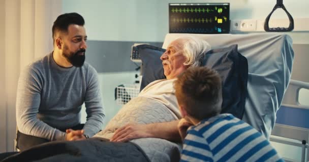 Homme âgé parlant avec son fils et son petit-fils à l'hôpital — Video