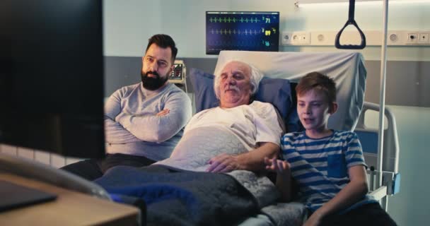 Senior man kijken wedstrijd met zoon en kleinzoon in ziekenhuis afdeling — Stockvideo