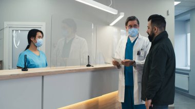 Asyalı resepsiyonist hastanın randevu almasına yardım ediyor