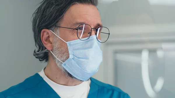 Medico maturo in maschera che parla con il paziente alla reception nel centro medico — Foto Stock