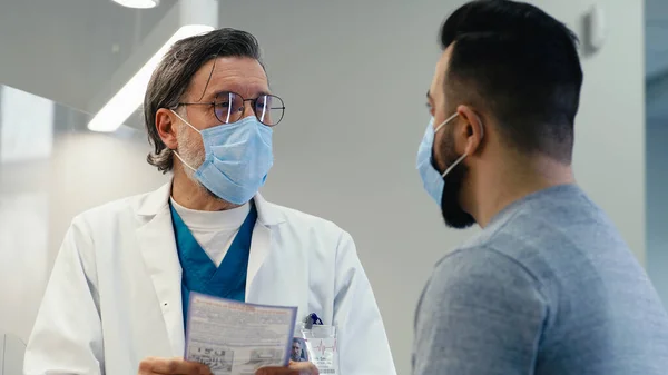 Maskeli olgun bir doktor hastaya reçete yazıyor. — Stok fotoğraf