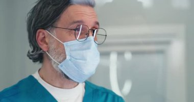 Maskeli olgun doktor, resepsiyondaki hastayla konuşuyor.
