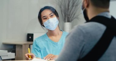 Asyalı resepsiyonist yaralı adama yön gösteriyor