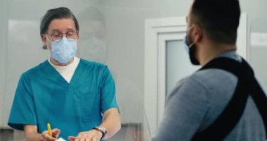 Hasta resepsiyondaki yaralı hastaya reçete veren erkek doktor