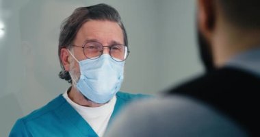 Orta yaşlı doktor, resepsiyonda hastayla görüşüyor.
