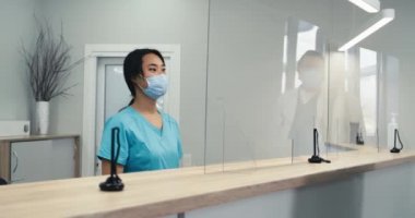 Asyalı resepsiyonist hastanın randevu almasına yardım ediyor