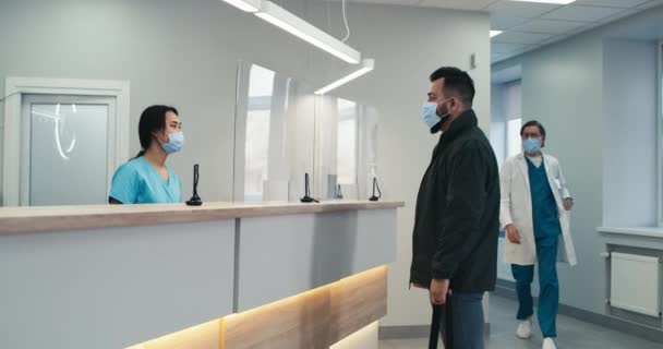 Multirracial recepcionista e médico ajudando o homem na clínica — Vídeo de Stock