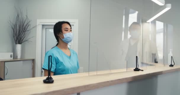 Азиатская секретарша помогает пациенту записаться на прием — стоковое видео