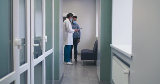 ผู้ป่วยชายคุยเรื่องการวินิจฉัยกับหมอในคลินิก — วีดีโอสต็อก