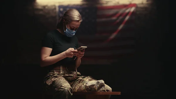 スマートフォンを使った仮面の軍人女性 — ストック写真