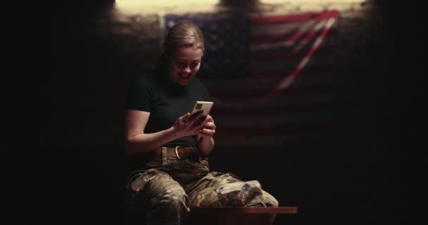 Délicieuse femme soldat assise sur un banc et faisant un appel vidéo — Video