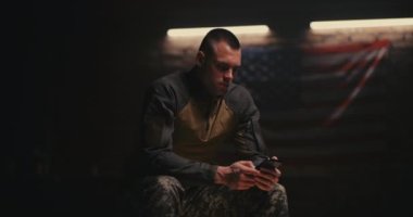 Askeri üste akıllı telefon kullanan yorgun asker.