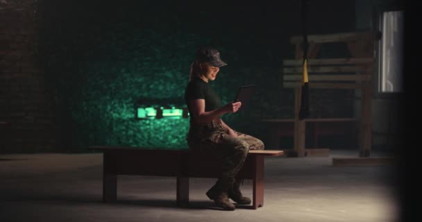 Militar mulher fazendo chamada de vídeo no banco no ginásio — Vídeo de Stock