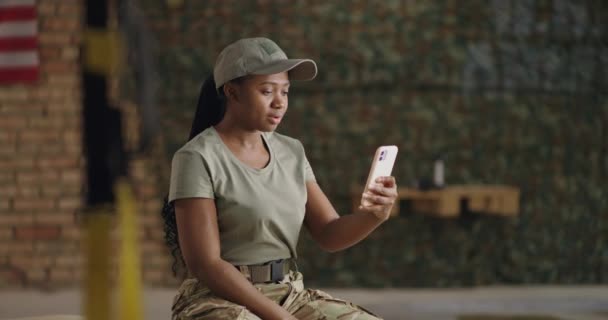 Feliz mujer militar afroamericana haciendo videollamada en el gimnasio — Vídeos de Stock