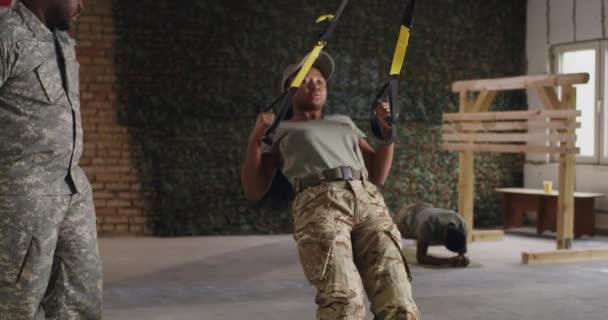 Soldado negro haciendo ejercicio con cuerdas de entrenamiento cerca del entrenador — Vídeo de stock