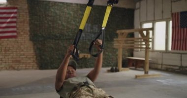 Siyah kadın asker halatlarla egzersiz yapıyor.