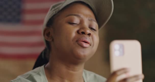 Счастливая черная женщина-солдат обсуждает новости с онлайн-другом — стоковое видео